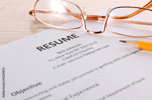 Closeup of resume with pencil and glasses on table