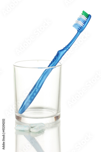 Toothbrush in glass and chewing gum isolated on white