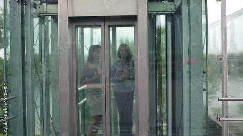 Two young businesswoman walking out of elevator