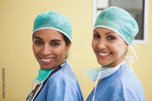 Two happy women wearing scrubs in hospital room