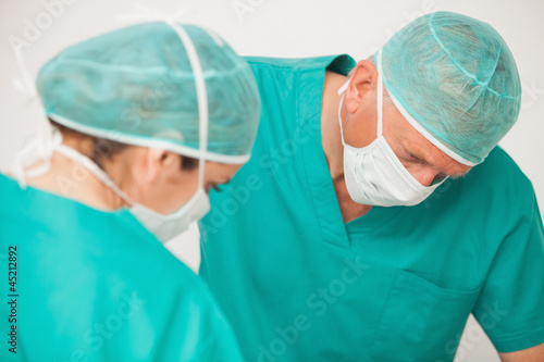 Two surgeons looking down on patient