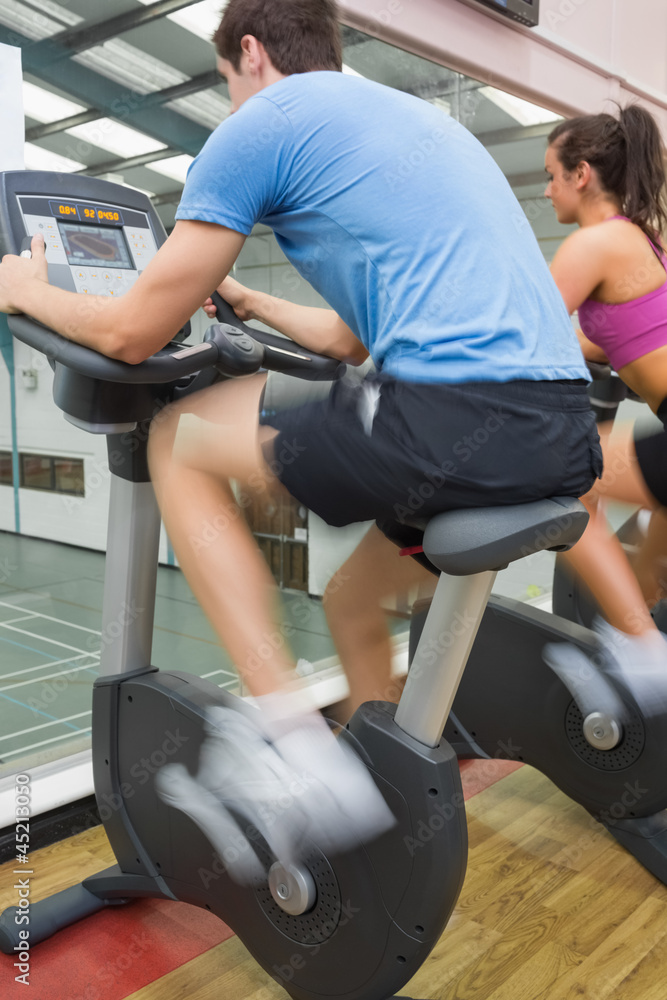 Man and woman riding on an exercise bike Man and woman riding on an exercise bike