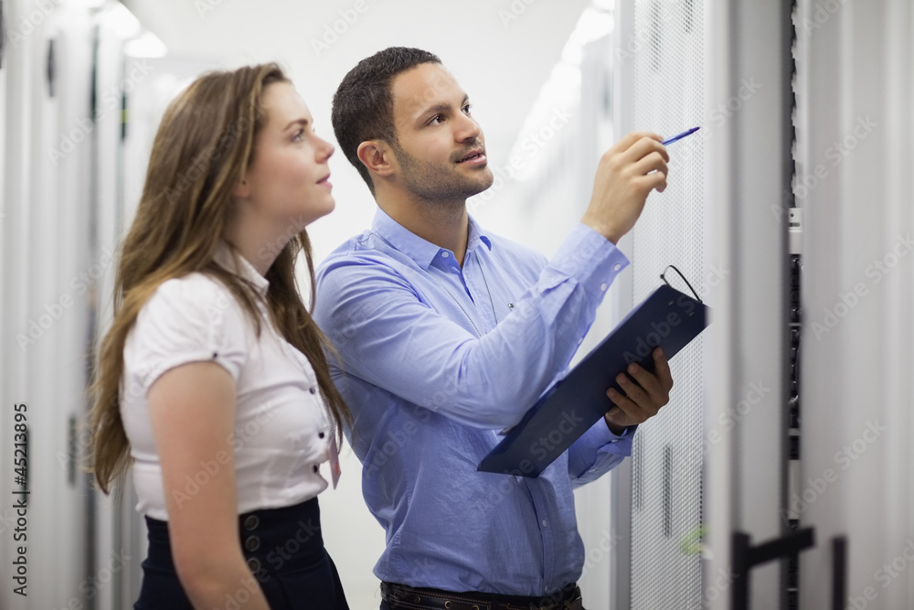 Technicians with clipboard looking at servers Technicians with clipboard looking at servers