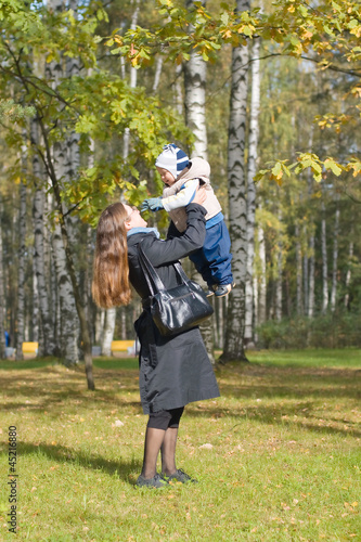 Мать держит на руках маленького сына в осеннем парке © papagoshi