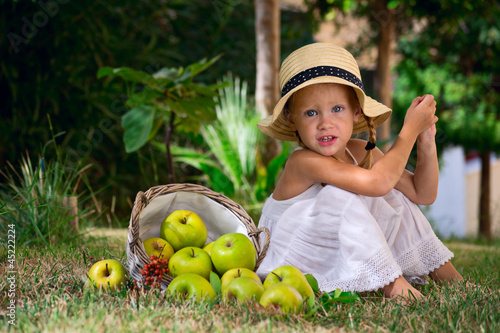 Девочка сидит на траве с корзиной яблой