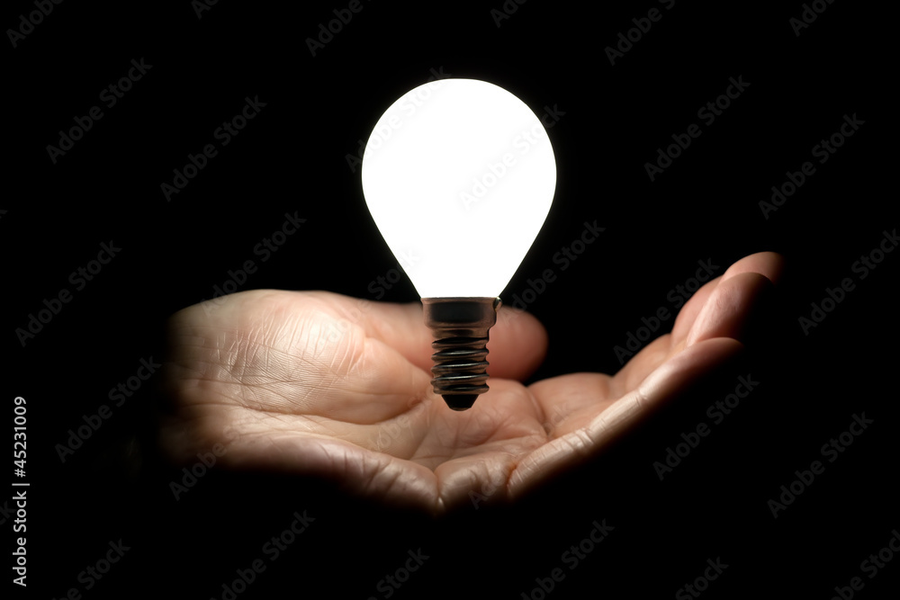 Floating lightbulb above hand on black background Floating lightbulb above hand on black background