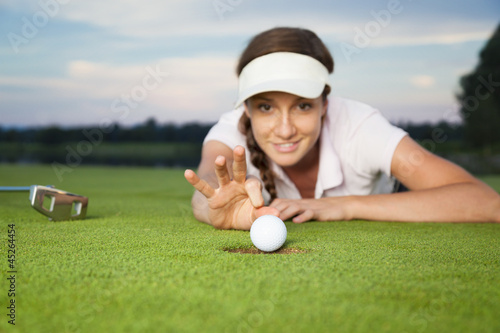 Girl golfer making a trick on green.