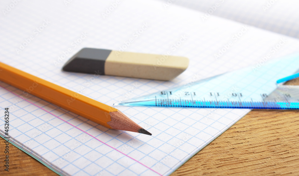 closeup of pencil notebook and eraser on wooden desk closeup of pencil notebook and eraser on wooden desk