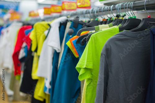 Variety of color T-shirts on stands in supermarket