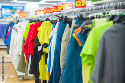 Color T-shirts and sport trousers on stands in supermarket