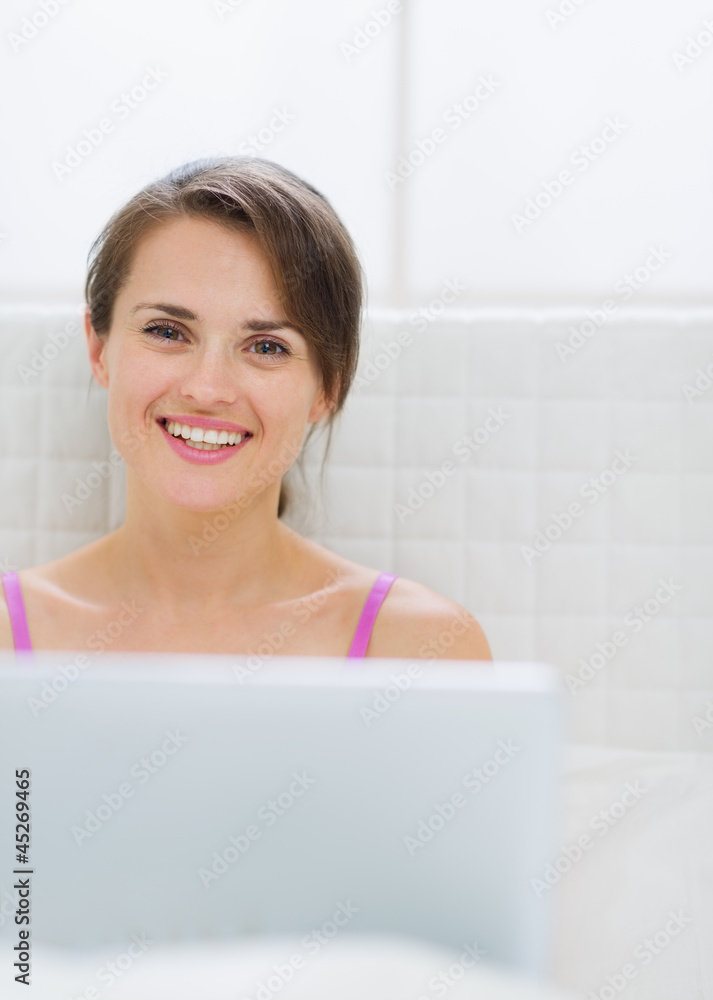Portrait of happy young woman with laptop in bed Portrait of happy young woman with laptop in bed