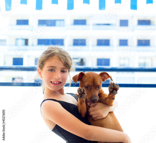 Brunette kid girl in swimsuit playing with dog photo