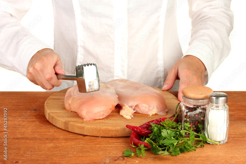 Chef beats meat on wooden table Chef beats meat on wooden table