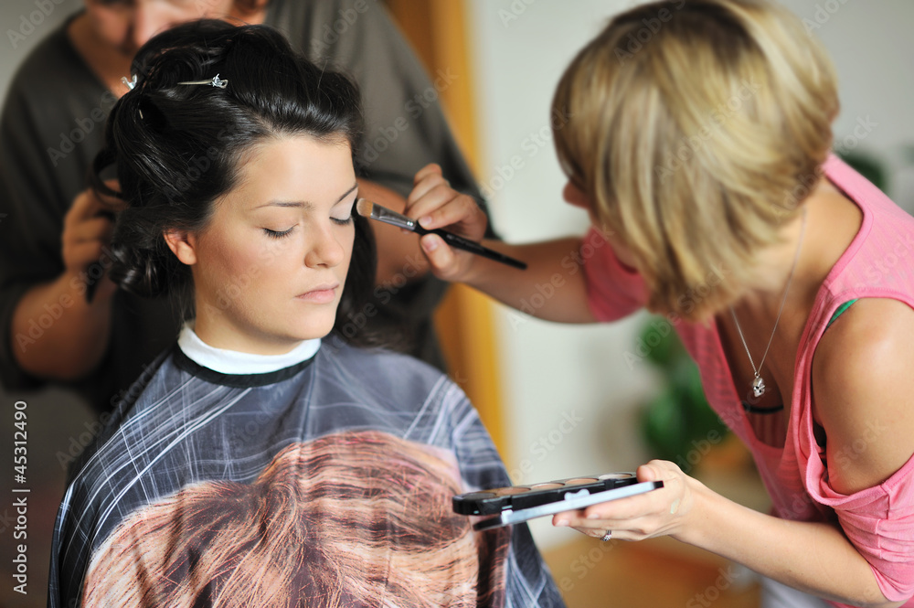 Young beautiful bride applying wedding make-up by make-up artist Young beautiful bride applying wedding make-up by make-up artist
