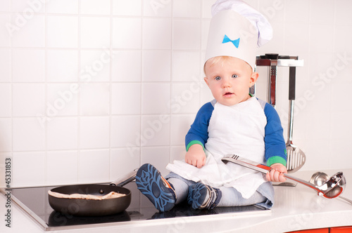Little baby chef in the cook hat with metal ladle