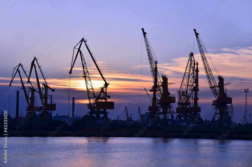 Port cargo crane over sunset sky background