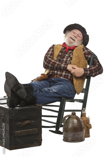 Happy old cowboy sits in rocking chair with feet up
