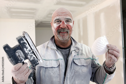 Handyman covered in dust after sanding room photo