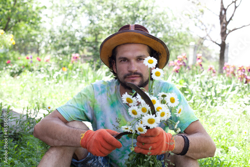 Man holding the camomile bouquet and the sickle