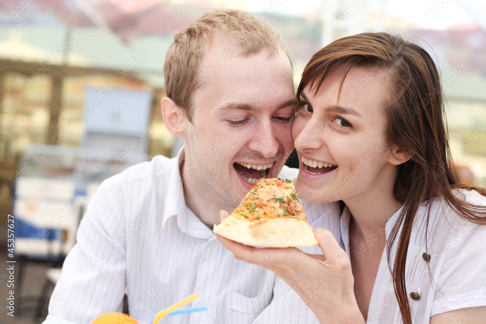 Young couple eating pizza in cafe