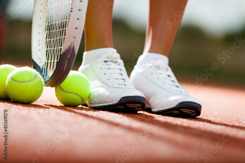 Legs of athlete near the tennis racket and balls © Karramba Production