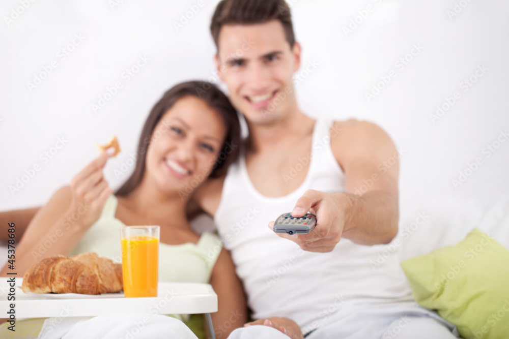 Couple having breakfast and watching TV