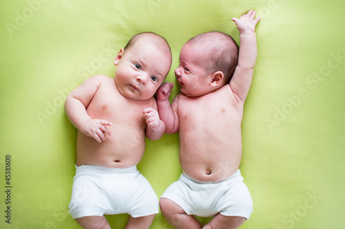 Foto funny twins brothers babies lying on green