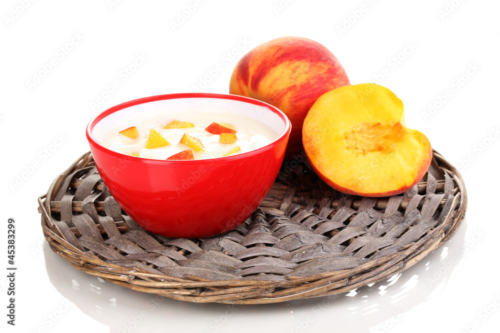 Yoghurt with peach in bowl on wicker mat isolated on white Yoghurt with peach in bowl on wicker mat isolated on white