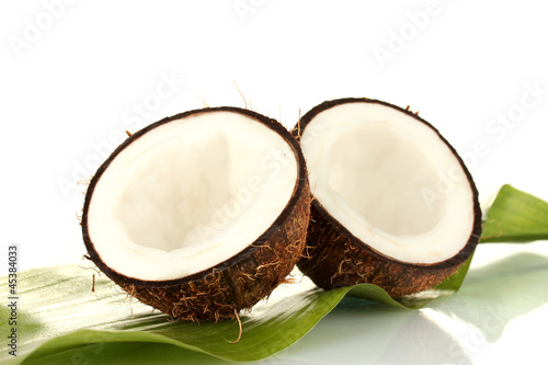 halves of coconut with green leaf on white background close-up