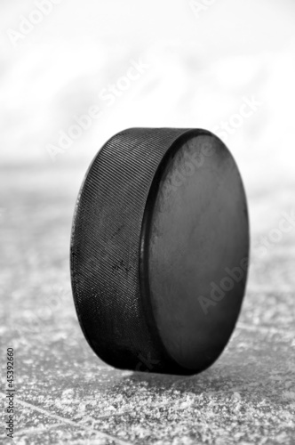 Photography black hockey puck on ice rink