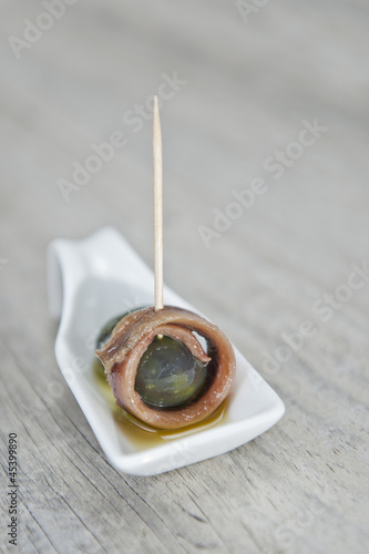 Pincho de anchoa y aceituna en cucharita de cerámica blanca photo