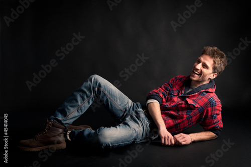 Young man laughing against black background.