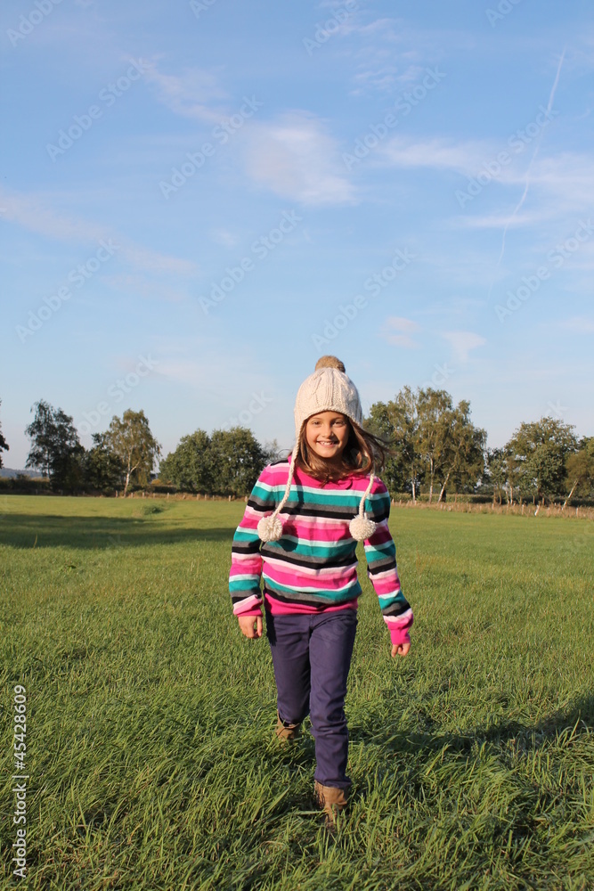 Fröhliches Mädchen im Herbst läuft über eine Wiese