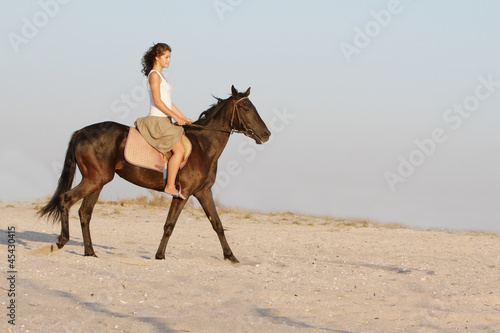 young happy woman riding horse on natural background © Alena Yakusheva