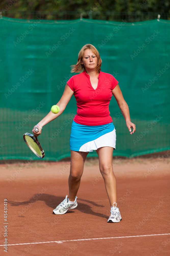 Young woman playing tennis on a dross field