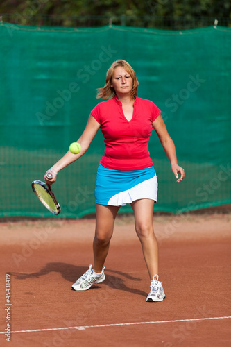 Young woman playing tennis on a dross field © Xalanx