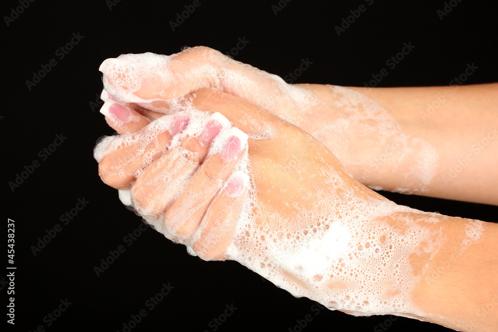 Woman's hands in soapsuds, on black background close-up Woman's hands in soapsuds, on black background close-up
