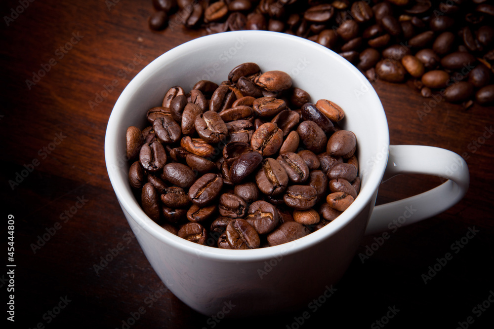 Fototapeta premium Kaffeetasse mit Bohnen auf Holztisch