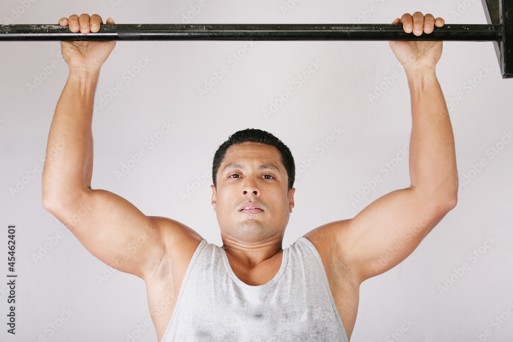 Naklejka premium Athlete pull oneself up on gym background