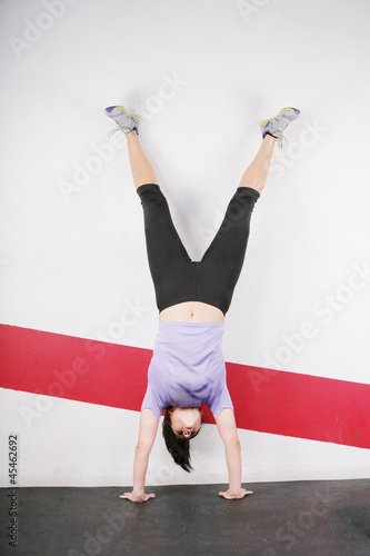 Tablou canvas Brunette handstand woman isolated on gym