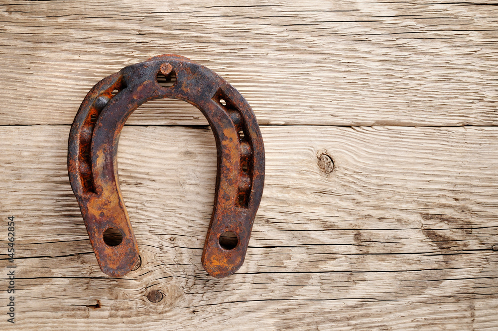 Old rusty horseshoe on wooden background Old rusty horseshoe on wooden background