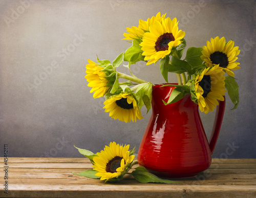Fototapeta Naklejka Na Ścianę i Meble -  Beautiful sunflower bouquet in red jug on wooden tabletop.
