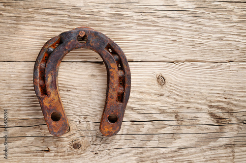 Old rusty horseshoe on wooden background photo