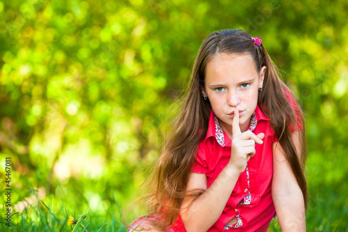 Young girl with her finger over her mouth  hushing.