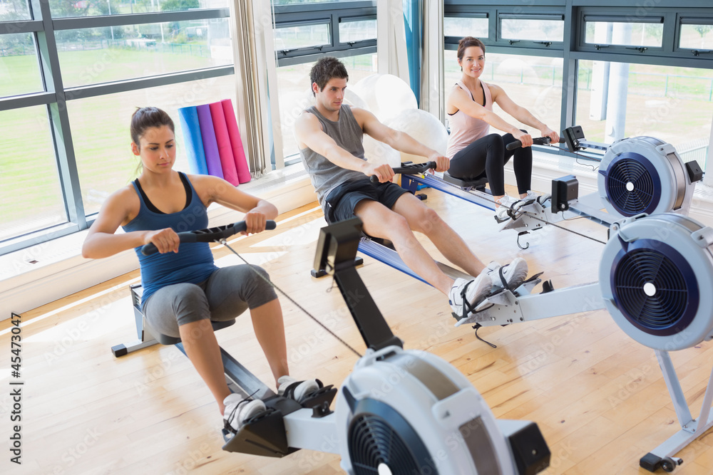 Fototapeta premium Three people on rowing machines