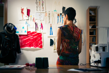 Female fashion designer contemplating drawings in studio