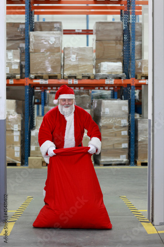 Santa Claus with large red sack in the gate to storehouse
