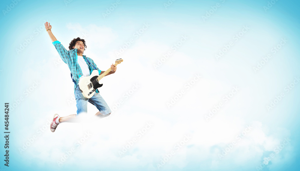 young man playing on electro guitar and jumping young man playing on electro guitar and jumping