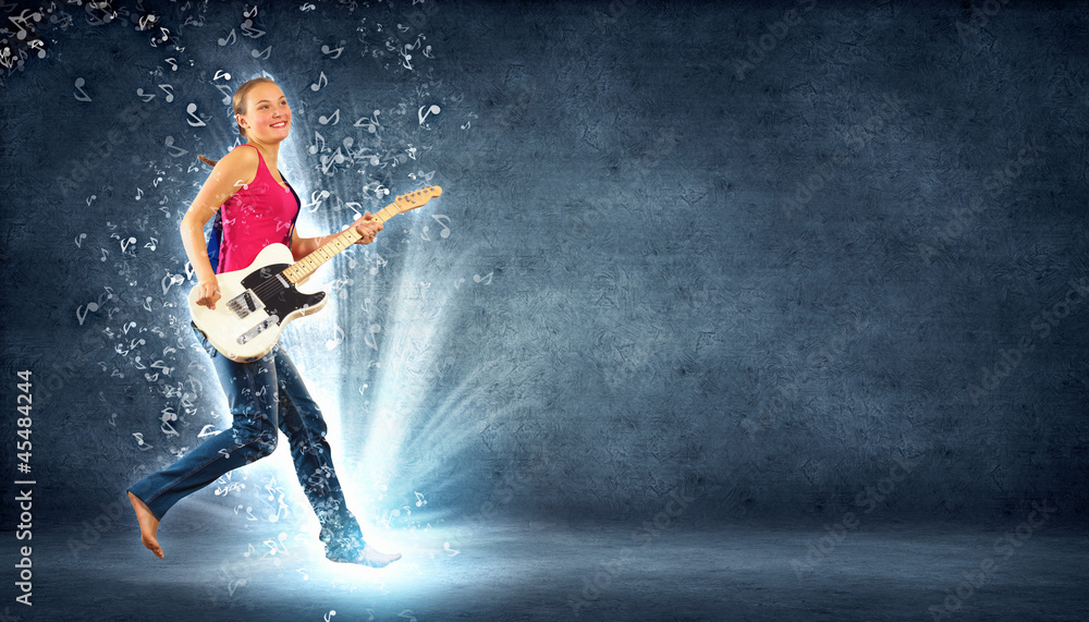 young woman playing on electro guitar and jumping