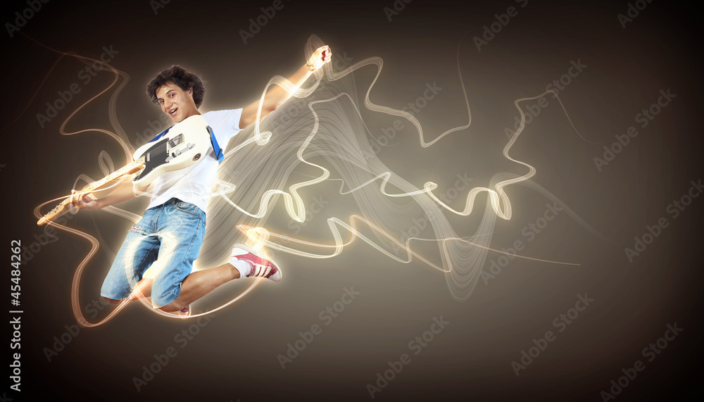 young man playing on electro guitar and jumping